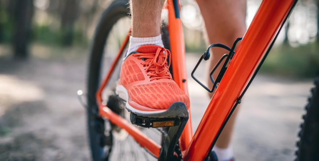 Pied placé sur une pédale de vélo pour illustrer le réglage de selle et l’alignement des appuis.