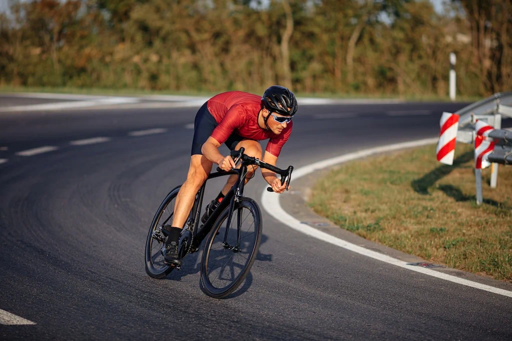 Cycliste en position sur vélo de route montrant le rôle du gainage et de la posture pour prévenir les douleurs.