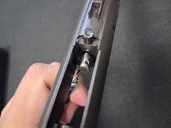Using a screwdriver to pull back the MWS nozzle spring assembly