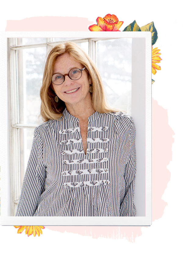 April Cornell, a blonde woman with dark-rimmed glasses in a striped top, is leaning in a white doorway