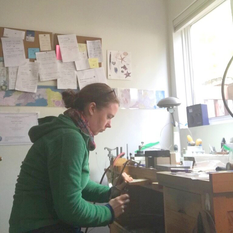 Abby Focht leaning over her artist's work bench