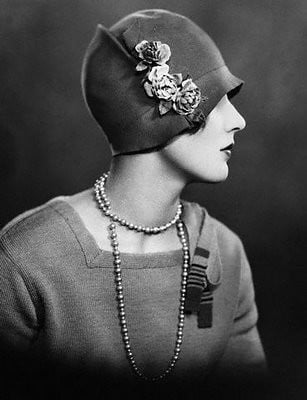 A lady in profile with a beautiful cloche hat adorned with flowers