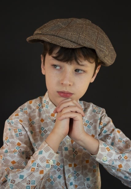 Boy wearing a print shirt and an oversize newsboy cap