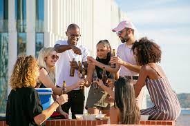 groupe de personnes trinquant sur une terasse dont l'un porte une casquette