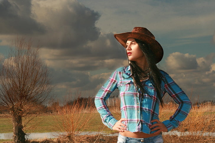 Cowgirl avec chemise à carreaux et un chapeau de cowboy marron