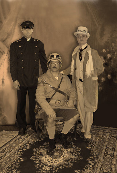 Black and white photo of three men sitting with hats including Pith Helmet
