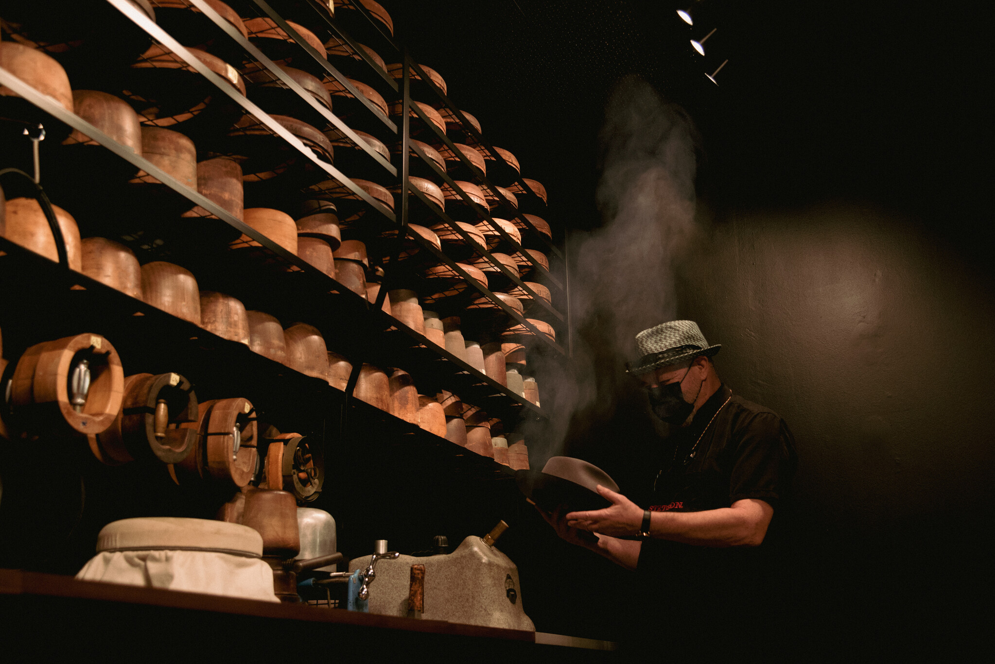 Hatter using steam to prepare a felt hat for reshaping