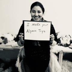 smiling woman with sign that says 'I made your alpaca toys'