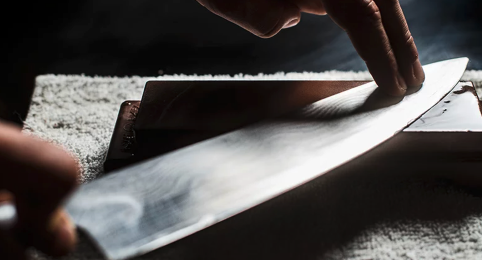 A person sharpens a knife using a wetstone.