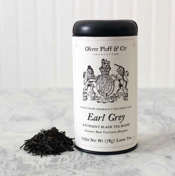 Oliver Pluff & Co. Loose Leaf Earl Grey Tea signature tin sits on a white marble surface with a small pile of tea leaves next to it. 