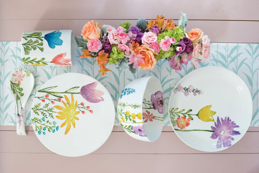 Vietri Fiori de Campo cereal plates and bowls on a pink tabletop with a blue-and-white table runner and flowers. 