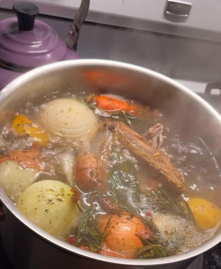 A pot of stock simmering on a stovetop