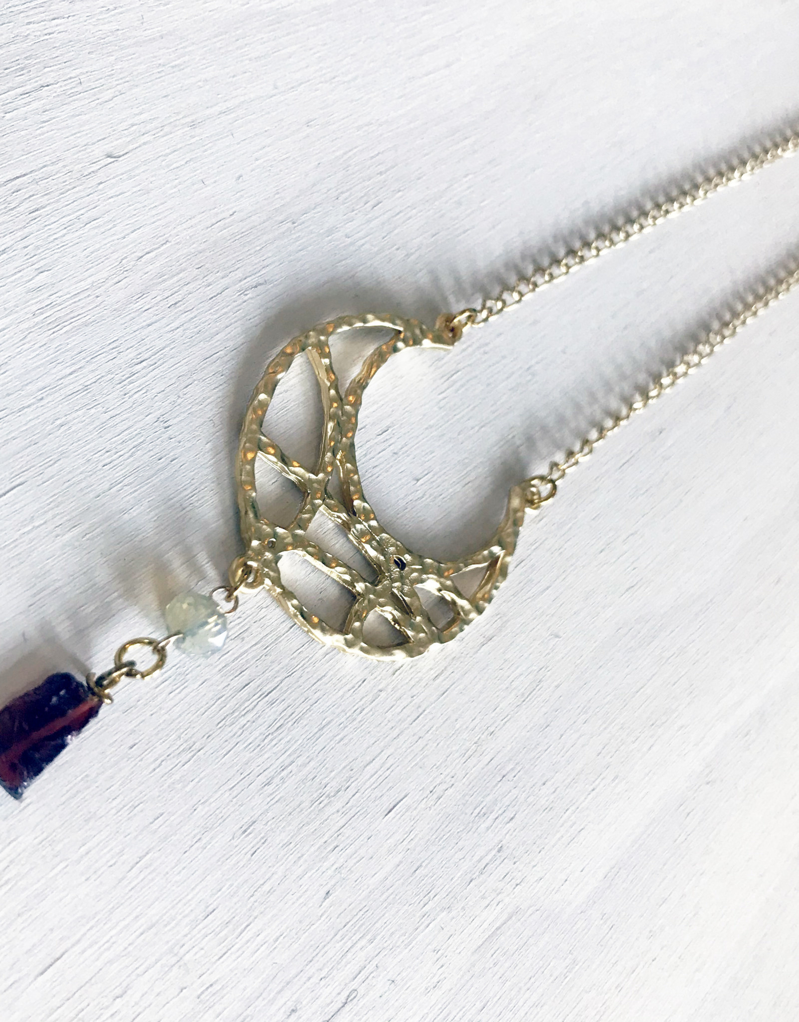 Devil May Wear Wandering Romani Textured Crescent Moon Necklace. Gold Plated pendant. Rough Garnet drop. Swarovski Crystal. Gold plated Chain. 27"