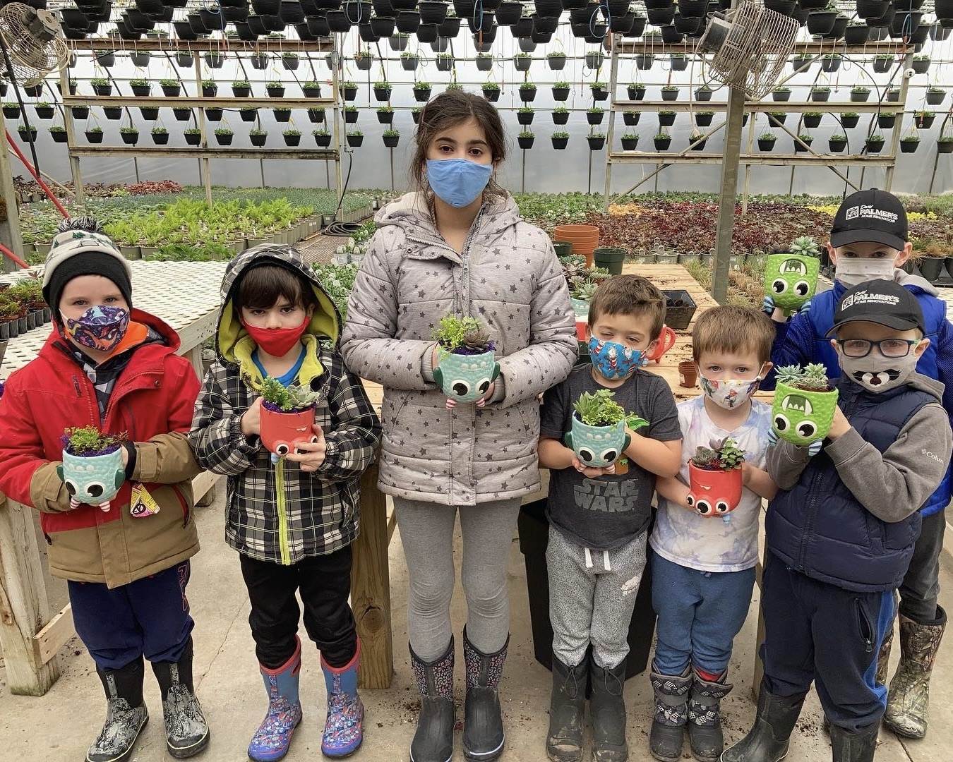 Children standing together showing their cute workshop plants.
