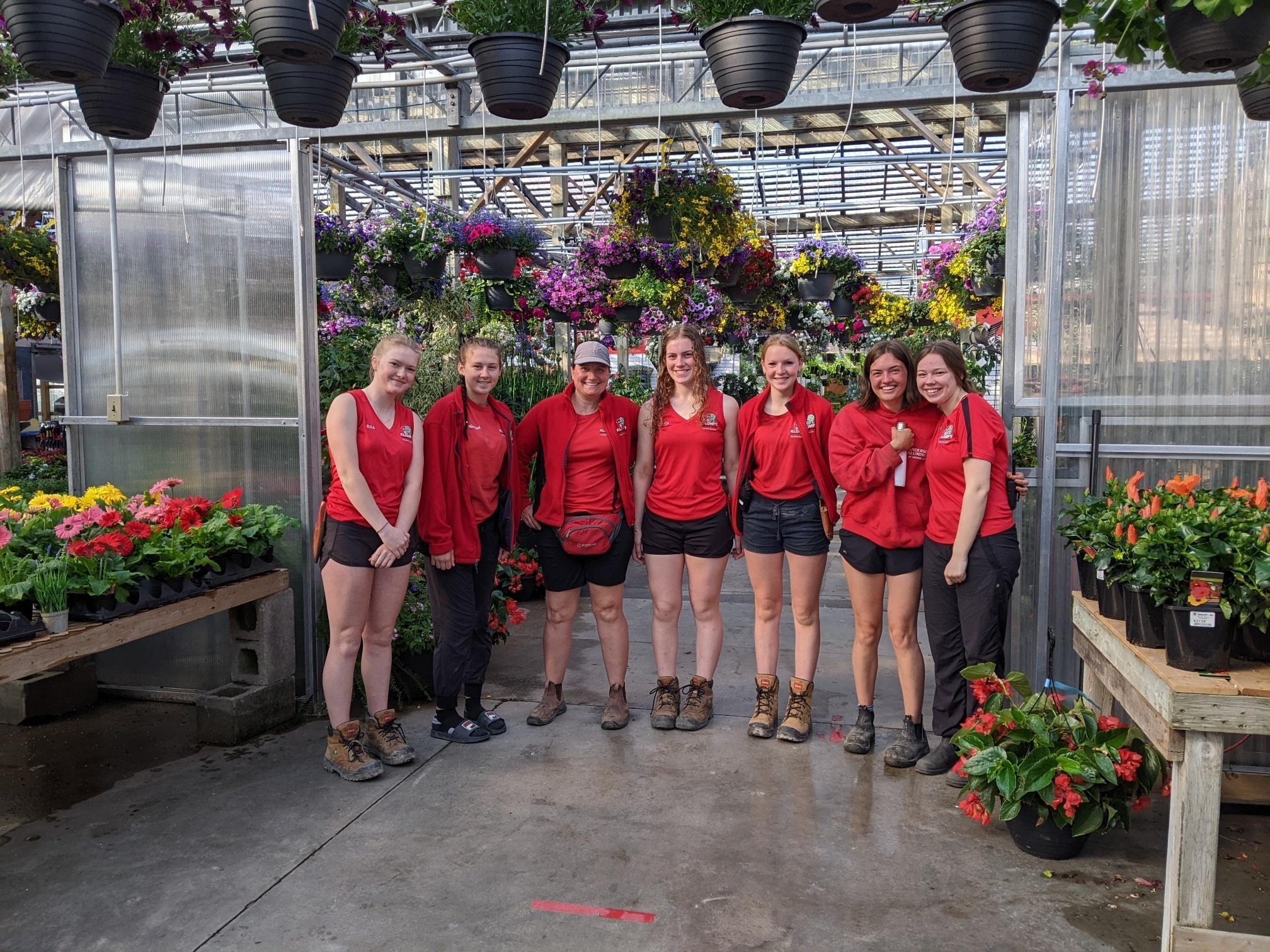 The Klomp’s staff members wearing their red and black uniforms in the store smiling and laughing together at work.