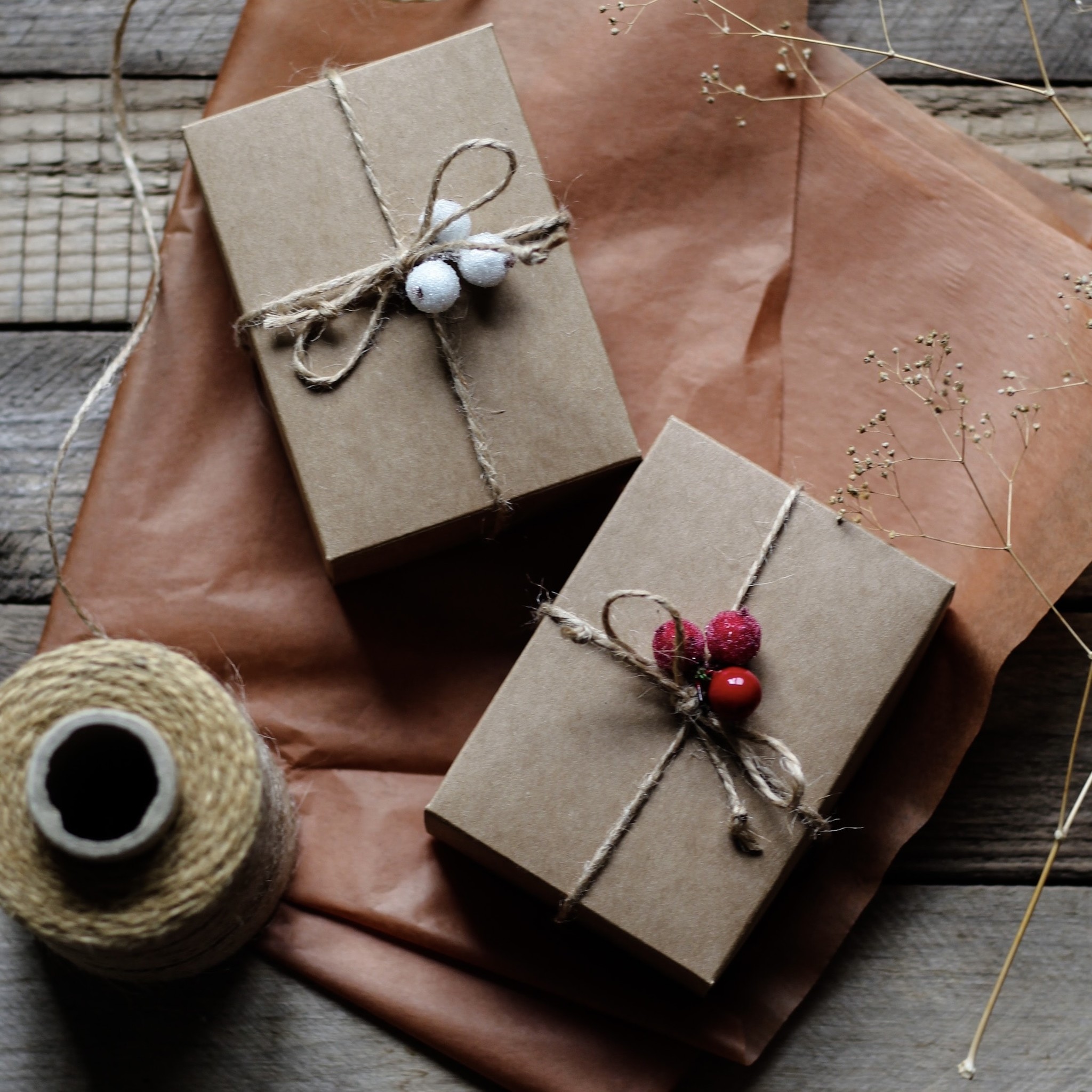 Two gift packages are elegantly wrapped with string and complimenting accessories attached. 