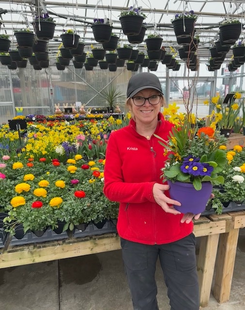 A Klomp’s employee smiling with a colourful hanging plant.