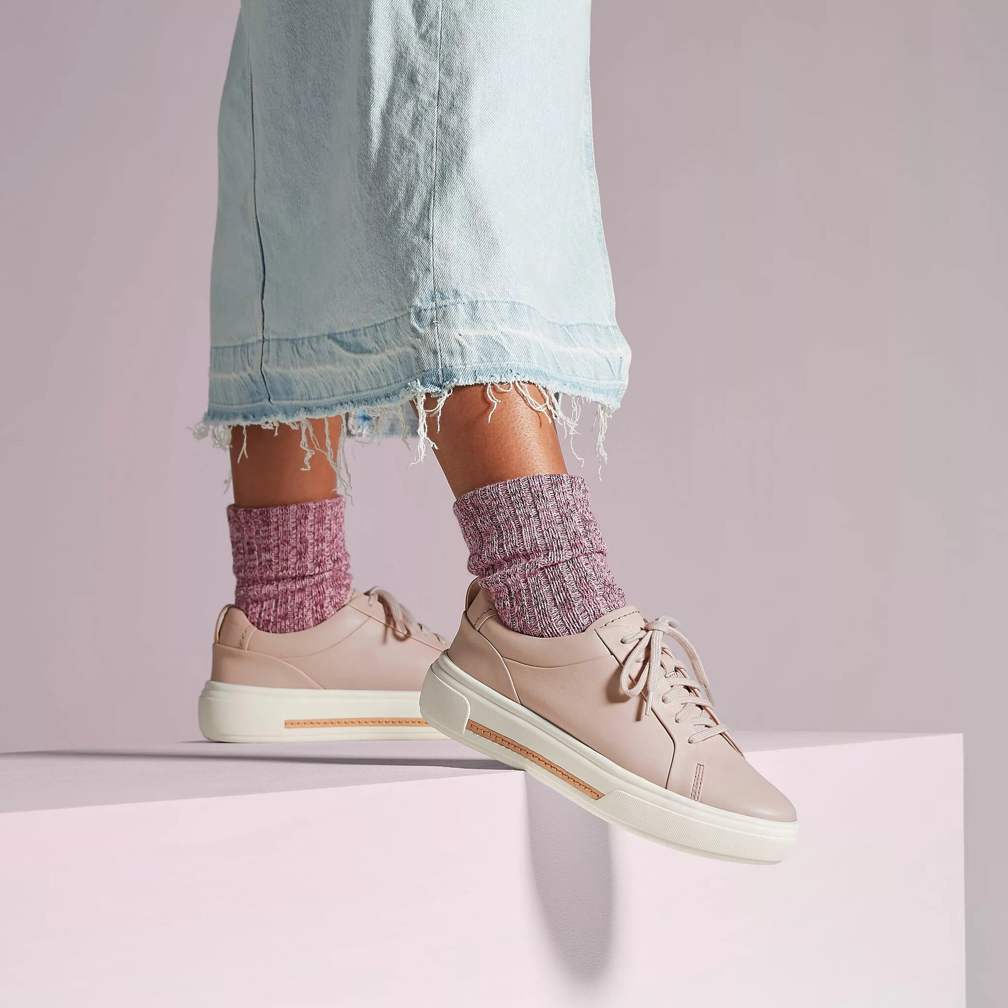 A model shows off Hollyhock Walk sneakers from Clarks in rose leather.
