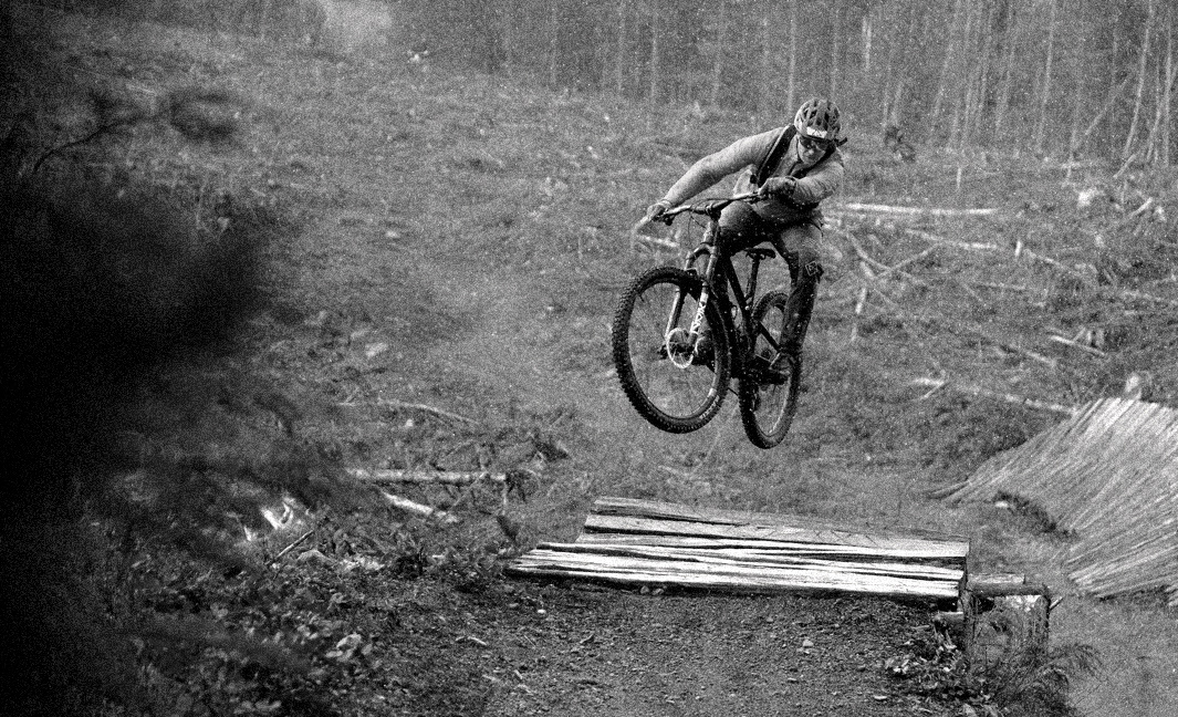 B&W photo of mountain biker jumping