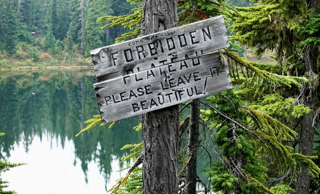 Mountain lake scene with close-up of wodden sign nailed to tree