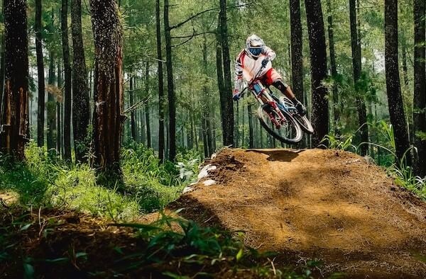 vélo de montagne de type enduro, cycliste saute un obstacle en forêt