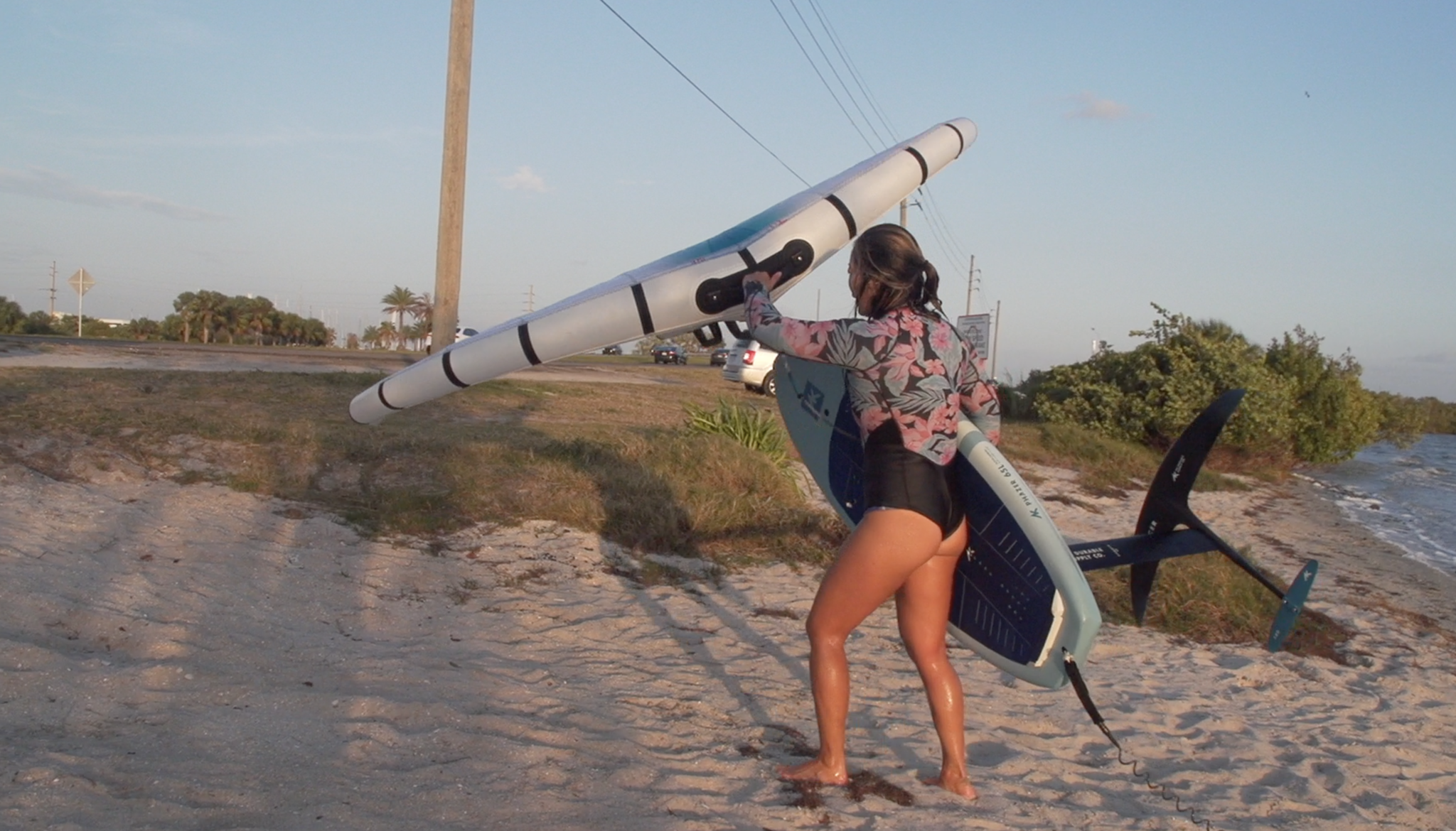 A female wingsurfer walking up the beach 