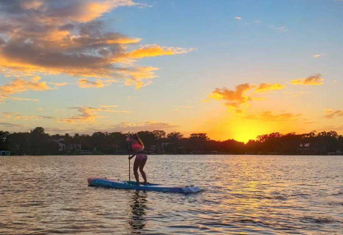 Paddleboarder on calm water at sunset near Cocoa Beach, Florida.