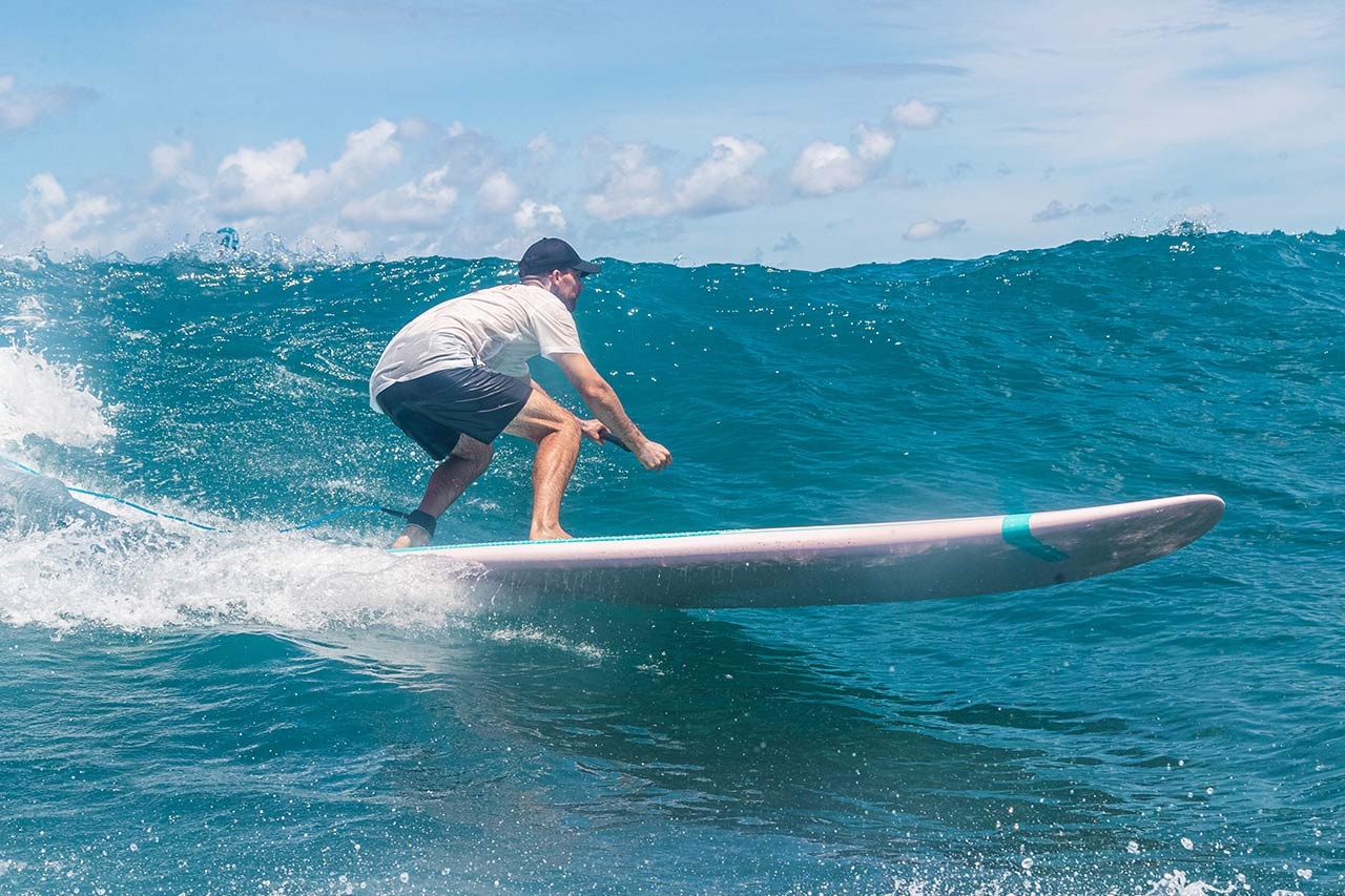 Rider trimming on a Starboard Go Surf paddleboard, highlighting the thin rail profile on a clean wave.