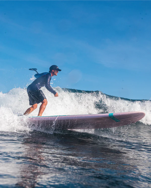 Rider carving a turquoise wave on the Starboard Go Surf, demonstrating small-wave surf performance.