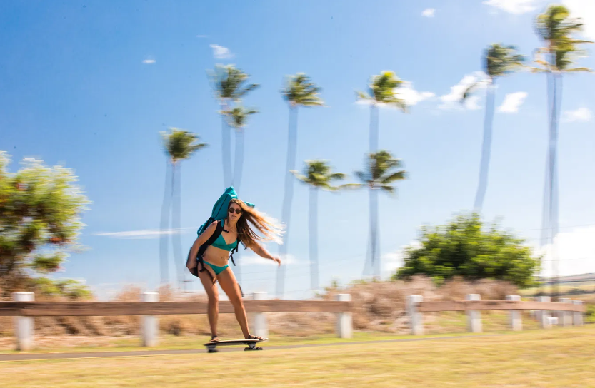 Woman skating with the Fanatic Fly Air Pocket Edition backpack, showing how lightweight and portable the inflatable SUP is for travel.