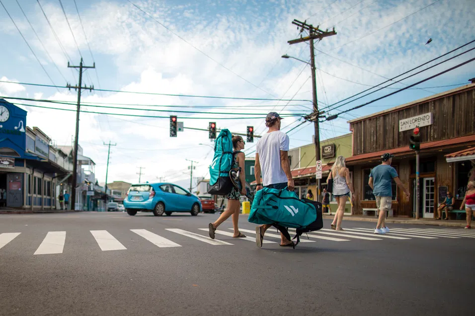 Travelers walking through town with Fanatic Fly Air Pocket Edition SUP bags, showing how easy the board is to carry.