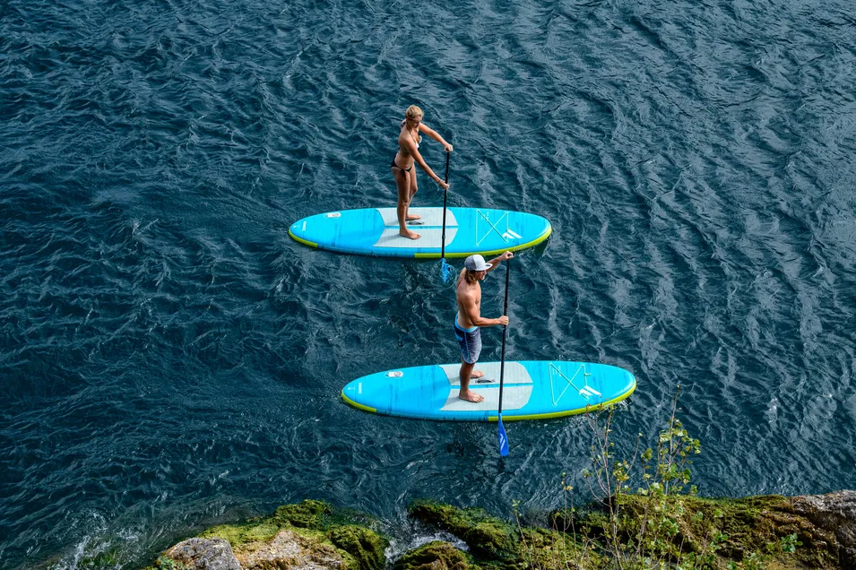 Two paddlers standing on Fanatic Fly Air Pocket Edition boards cruising along deep blue flatwater.