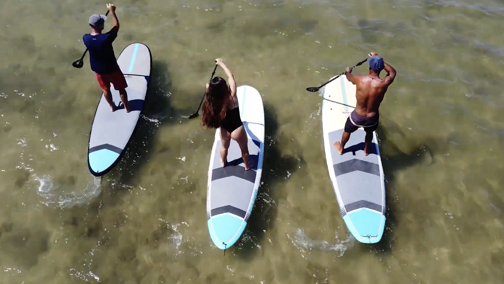 Three riders paddling Naish Nalu GTW stand up paddle boards together on shallow flatwater