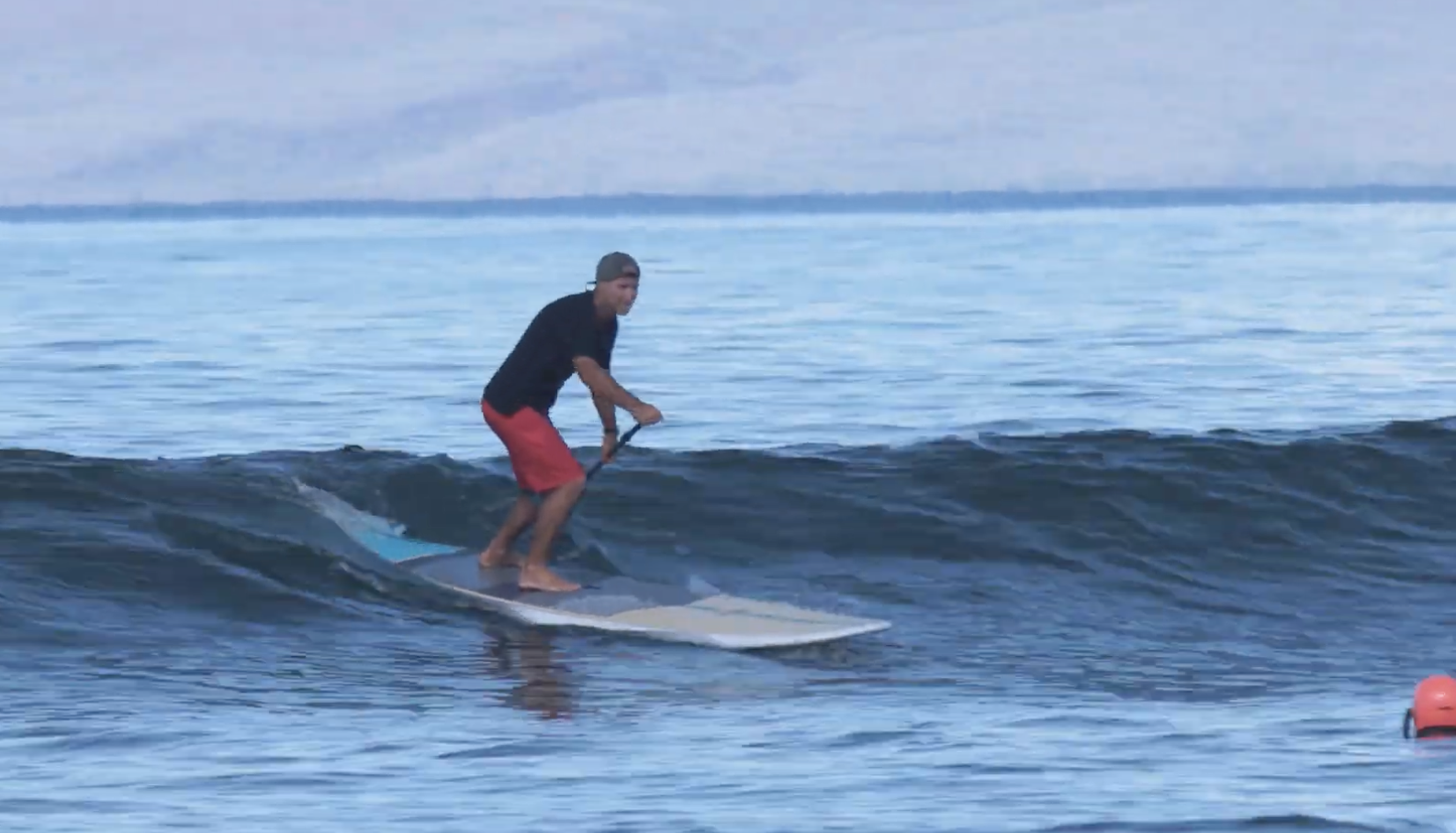 Paddler riding a small wave on a Naish Nalu 10'9 GTW surf-style SUP