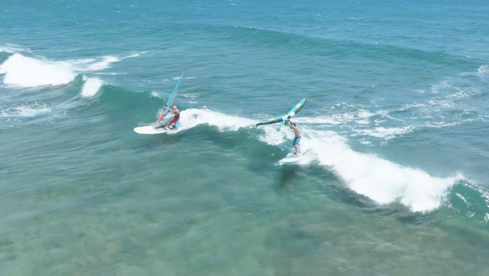 Windsurfer and wing foiler sharing a small wave, with the windsurfer on a Naish Nalu GTW board