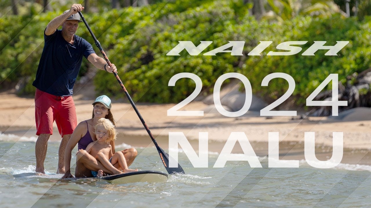 Adult paddling a Naish Nalu board with partner and child sitting on the nose in shallow water