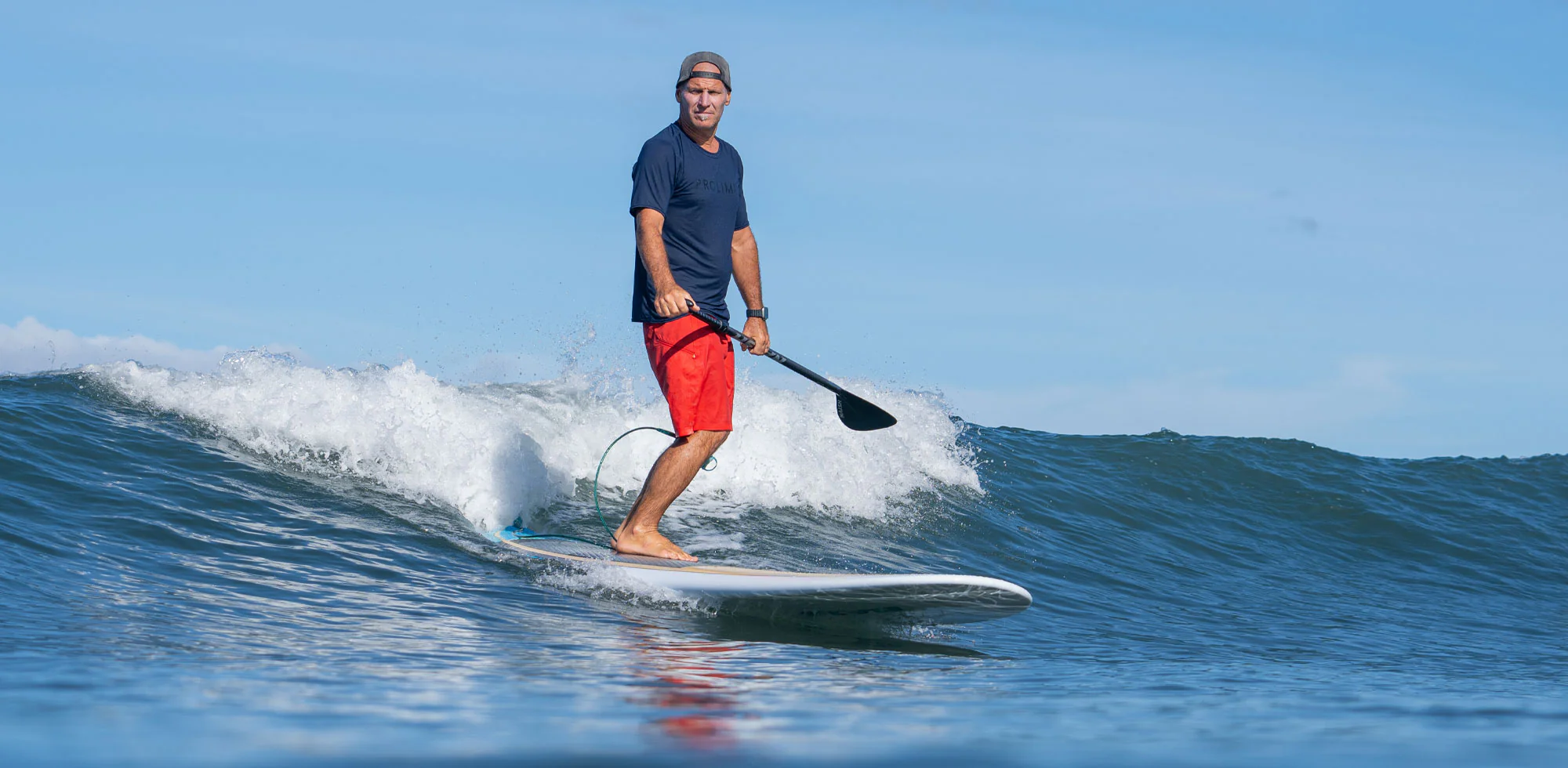 Man paddle boarding on a small ocean wave in Cocoa Beach showing balance and control