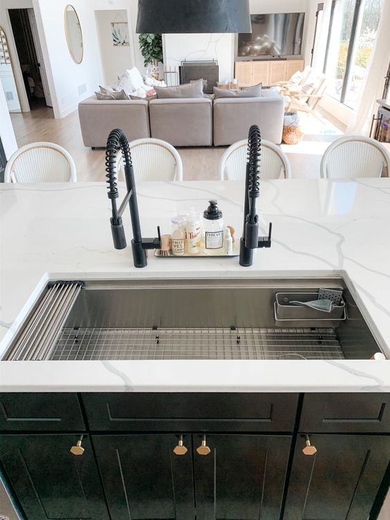 A workstation sink featuring a large basin, and two faucets placed in the middle of the island.