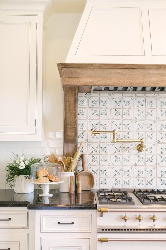 Blue and white patterned backsplash in a white kitchen with a large range hood.