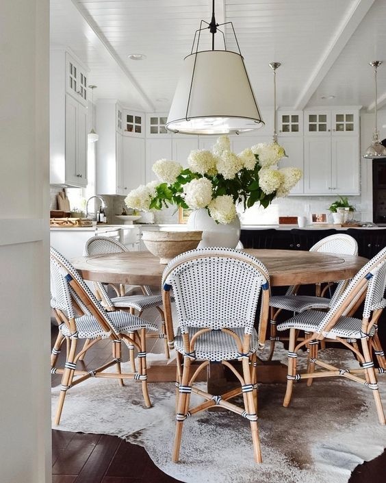 Wood round beach inspired table with large light fixture above.