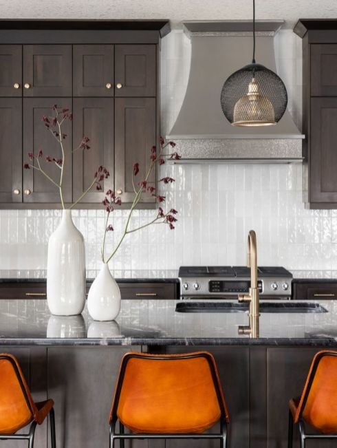 Modern kitchen with dark brown cabinetry and modern orange barstools