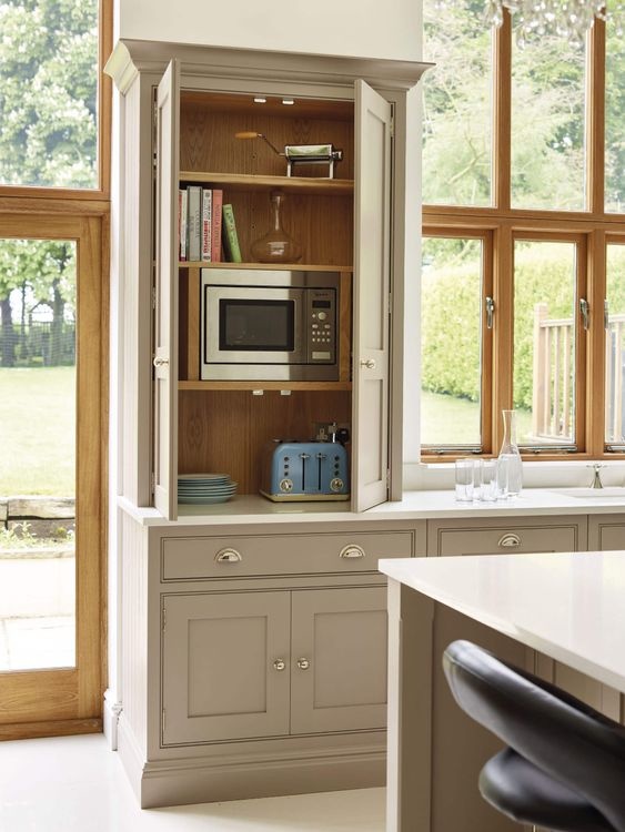 Beige cabinetry with cup pull handles, cabinets are open to show a hidden microwave