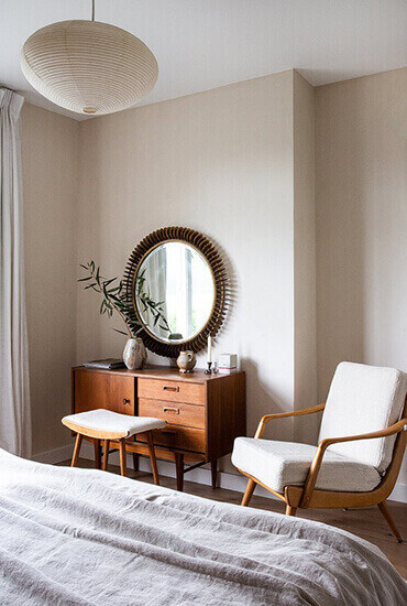 Mid-century modern bedroom with round mirror and wood chair