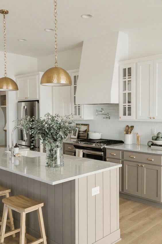 Bright white kitchen with large gold pendant lights over island