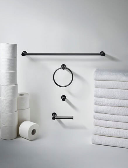 Matte black bath hardware surrounded by bath towels and tissue