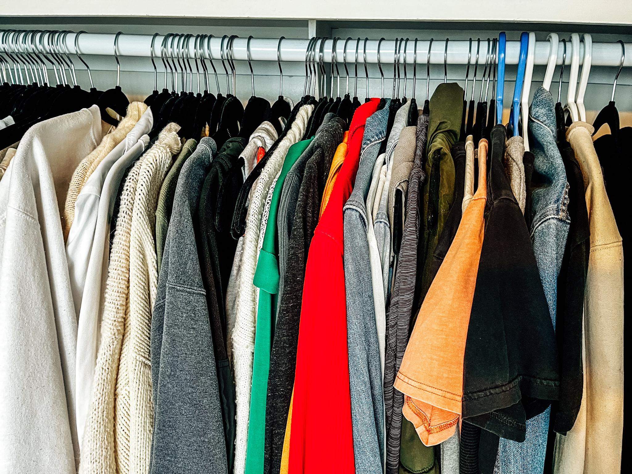 Closet featuring lots of clothes on a white closet rod