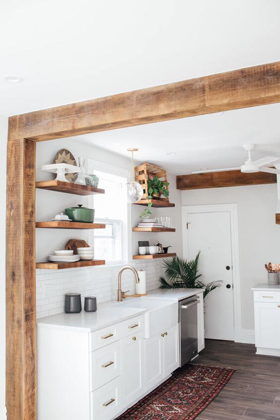 Bright white kitchen with wood shelves and wooden beam