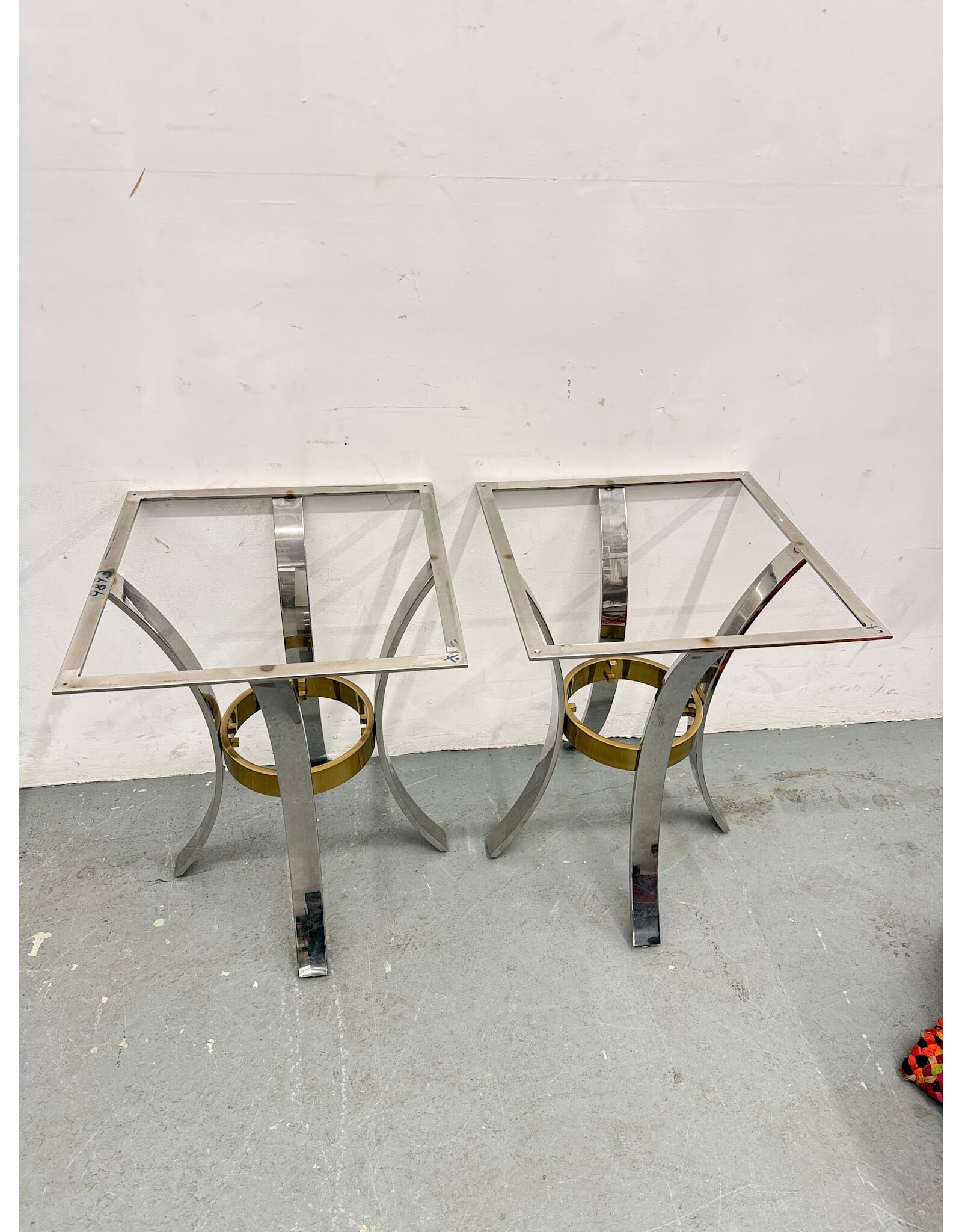 Mid-Century Modern accent tables featuring polished chrome arched legs and a brass ring stretcher