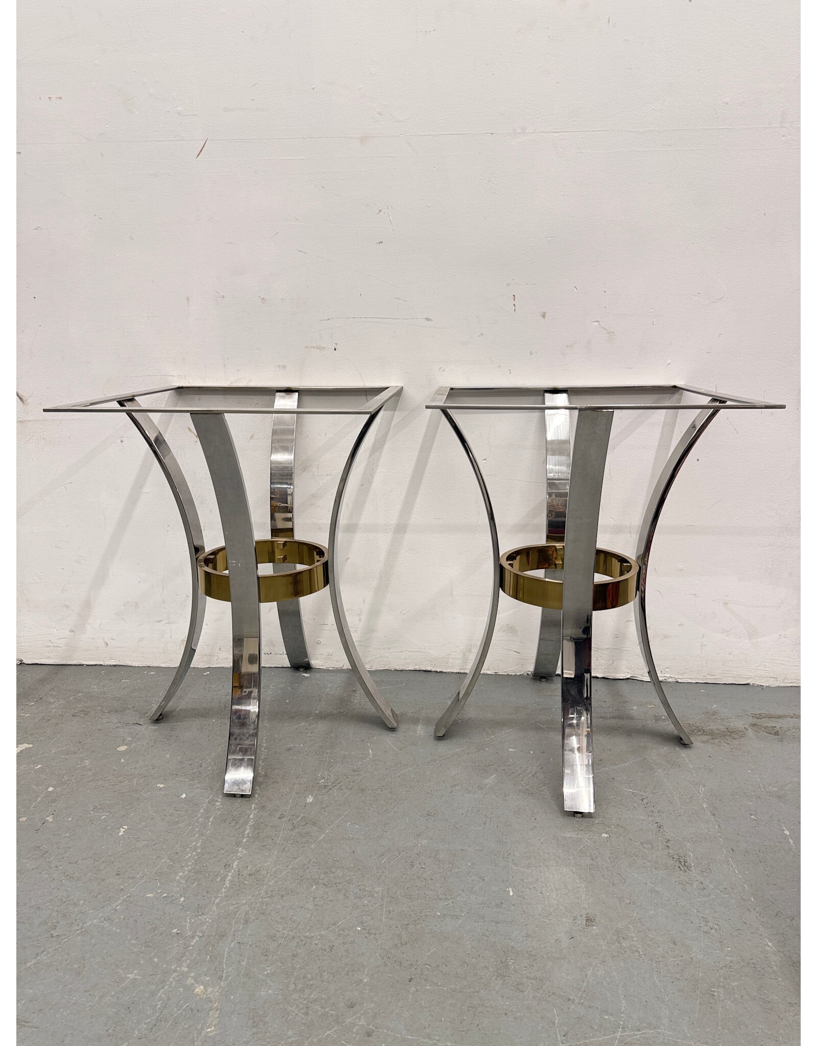 Mid-Century Modern accent tables featuring polished chrome arched legs and a brass ring stretcher
