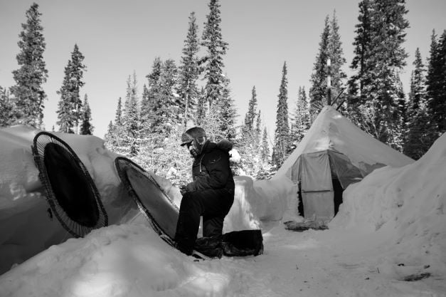 Man in snowy landscape working on stretched beaver pelt